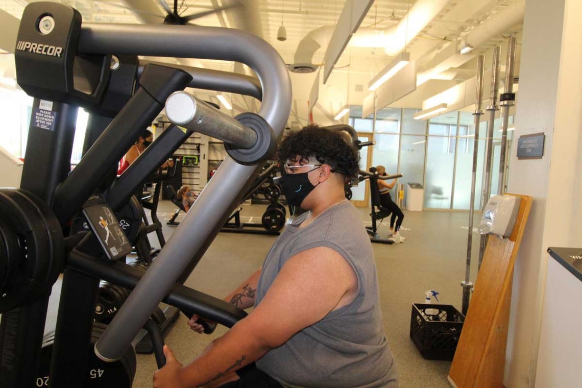 Patron wearing mask while using workout equipment