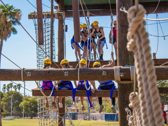 group on the high ropes course wearing yellow helmets and blue harnesses