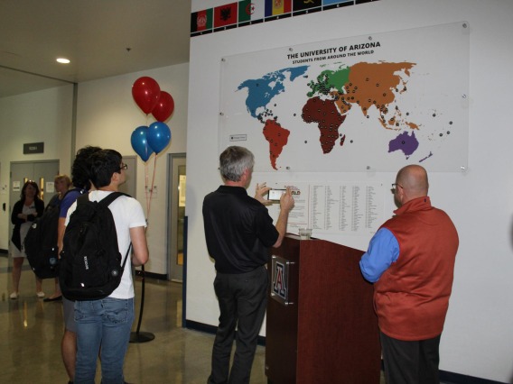 People viewing and taking pictures of "students from around the world" map at Campus Rec