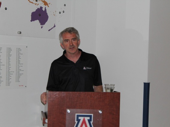 Brent White giving speech in front of "students from around the world" display