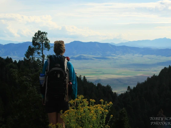 Hiker with back to camera, gazing out at mountain vista