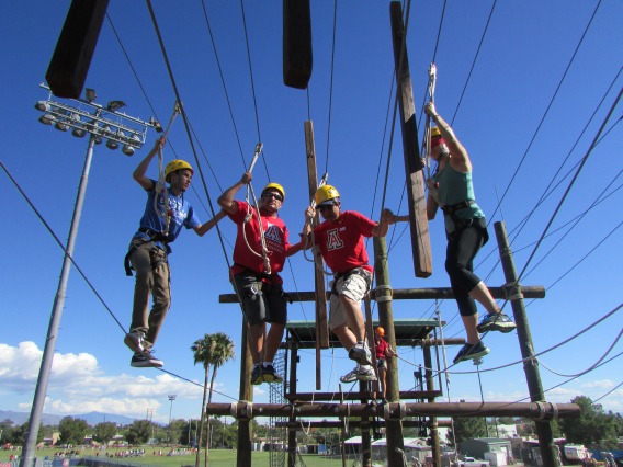 group on the high ropes course wearing yellow helmets and blue harnesses