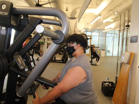 Patron wearing mask while using workout equipment