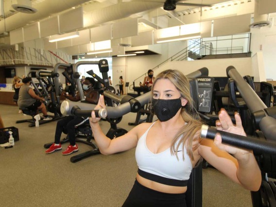 Patron wearing mask while using workout equipment alone