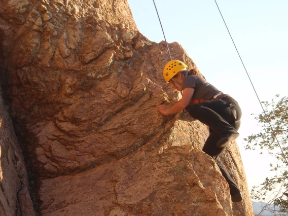 Climber ascending up the side of a cliff wall