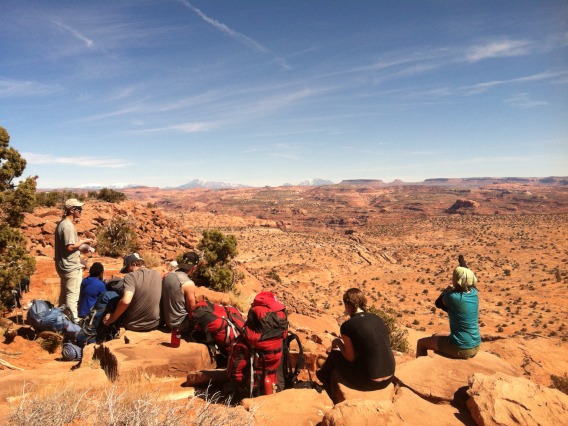 Group of hikers sitting on edge of cliff taking a break