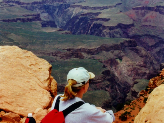 Hiker sitting on a cliff edge gazing at Grand Canyon