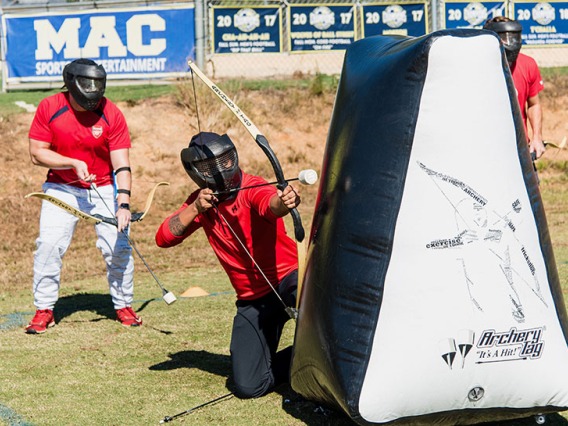 Archery Tag players hiding behind a inflatable paintball bunker preparing to shoot