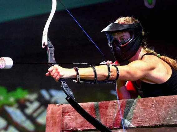Female participant drawing back an archery tag bow