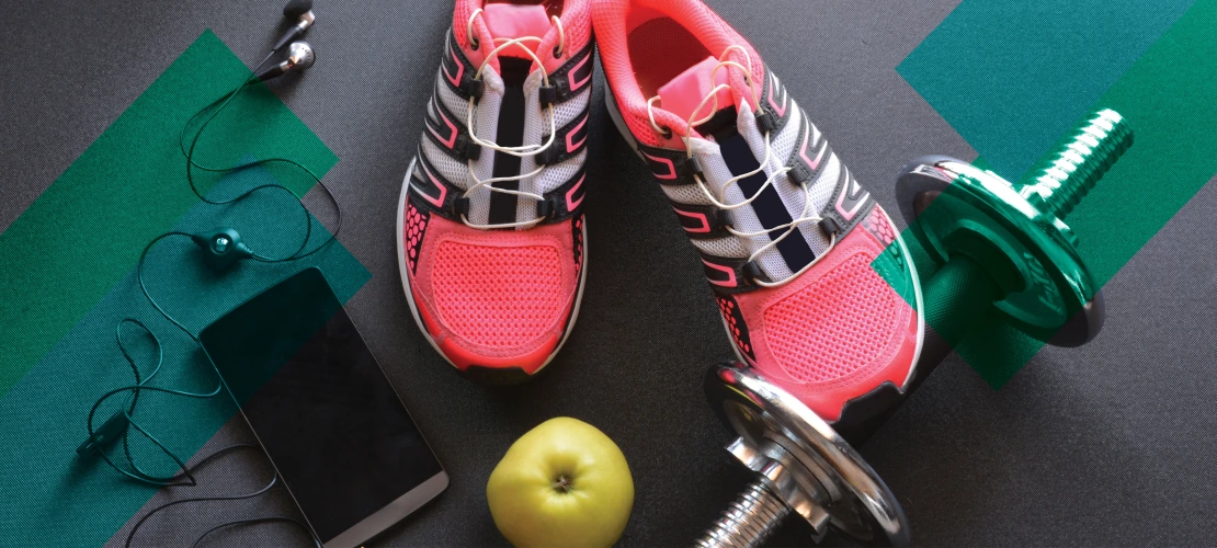 Photo of bright pink workout shoes, a small barbell, a smart phone with earbuds, and a yellow-green apple.