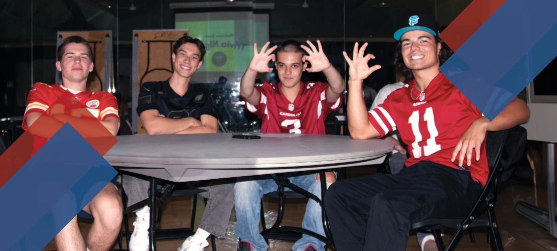 Four male students smiling and posing at a table.