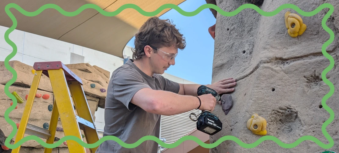 Student learning how to route-set a climbing wall.