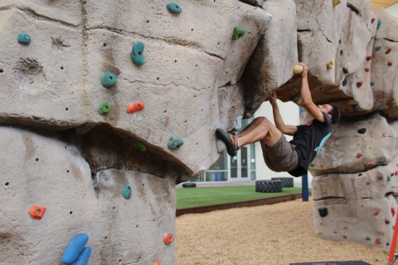 A rock climber hangs from a bouldering wall