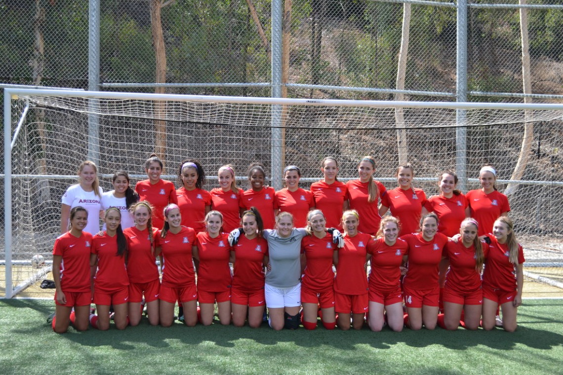 Women's soccer team posing for team photo in front of goal