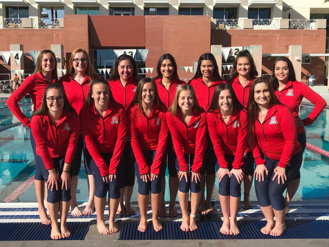 Synchronized swimming team posing for photo in front of pool
