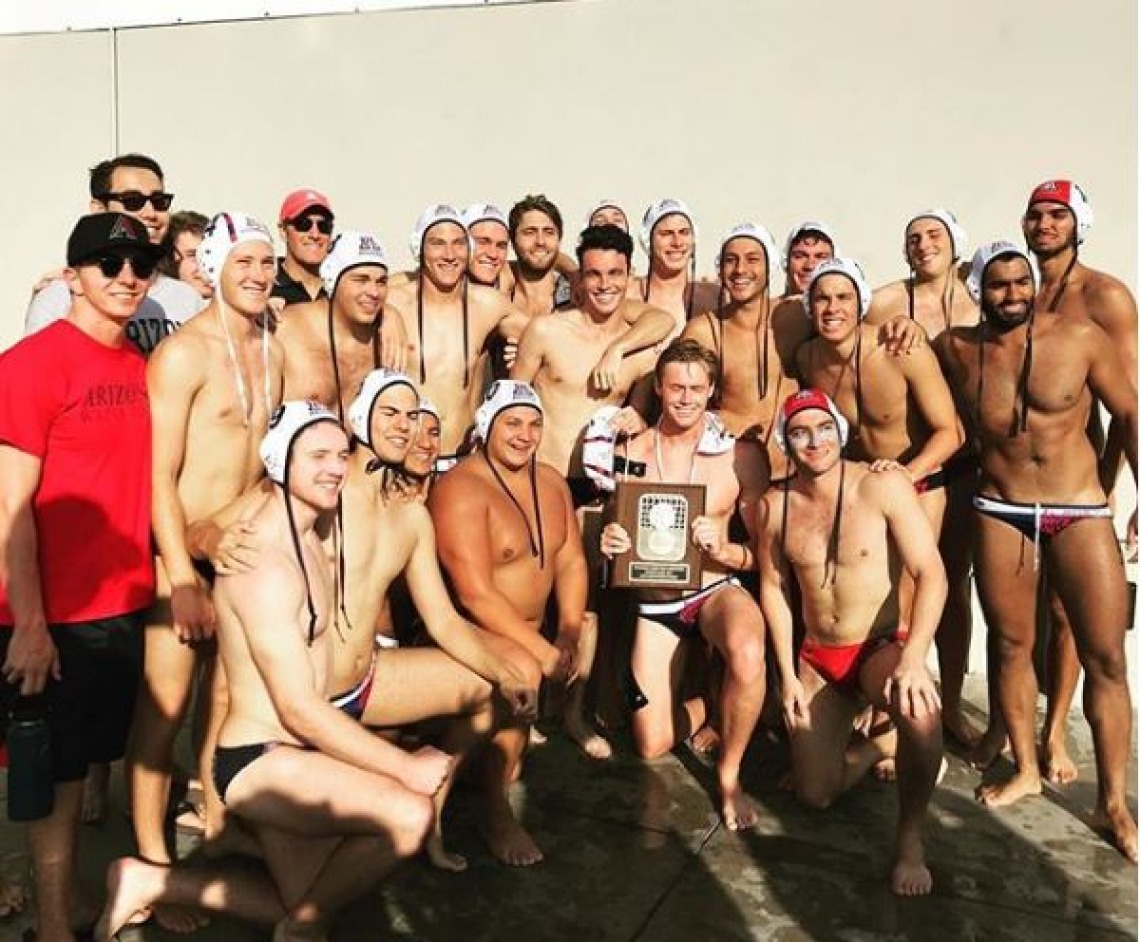 Men's water polo team posing for photo with plaque