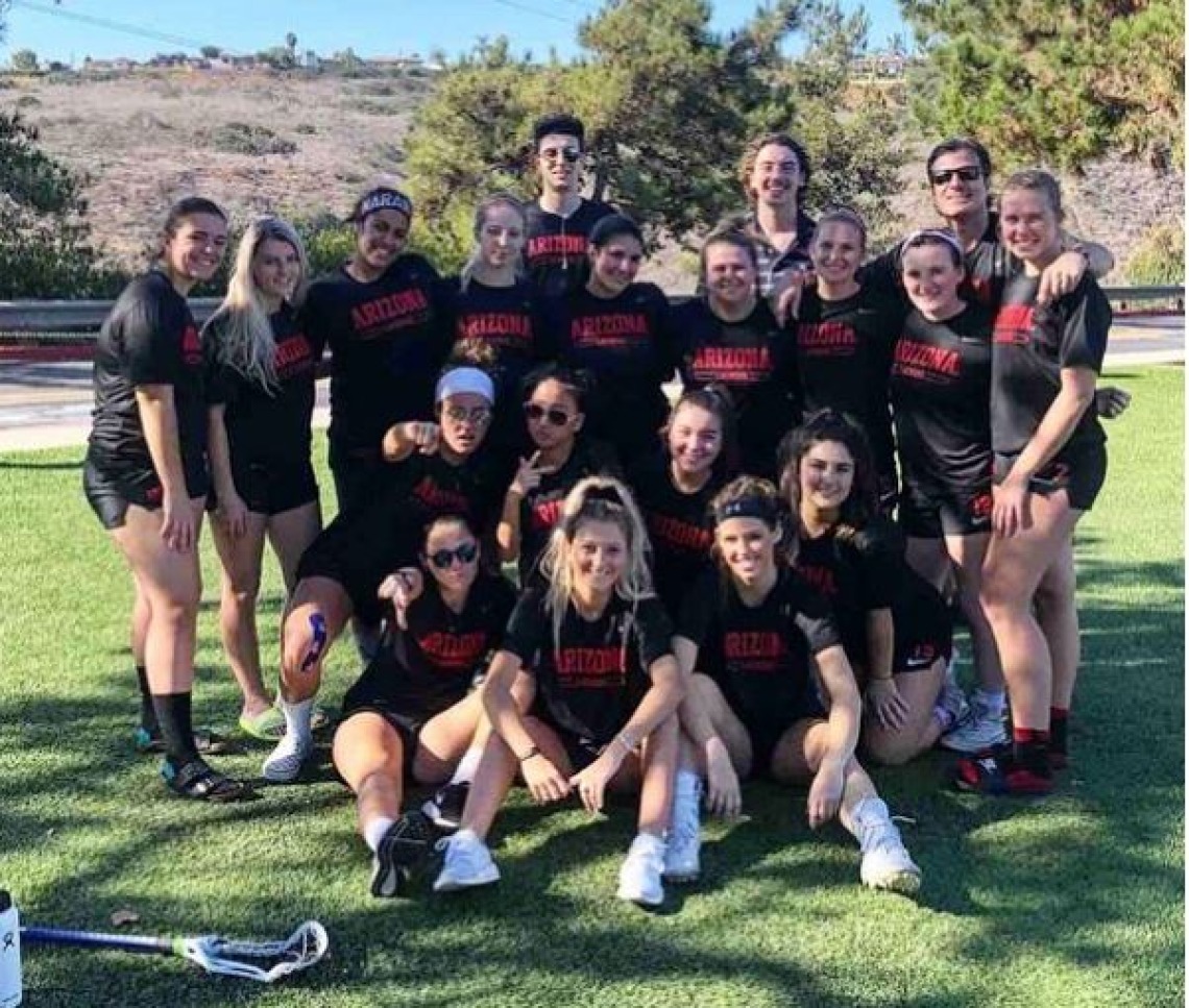 Women's lacrosse team posing for photo on field