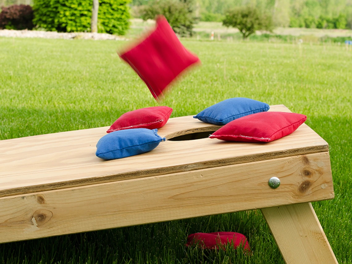 Hand bag being tossed onto cornhole board