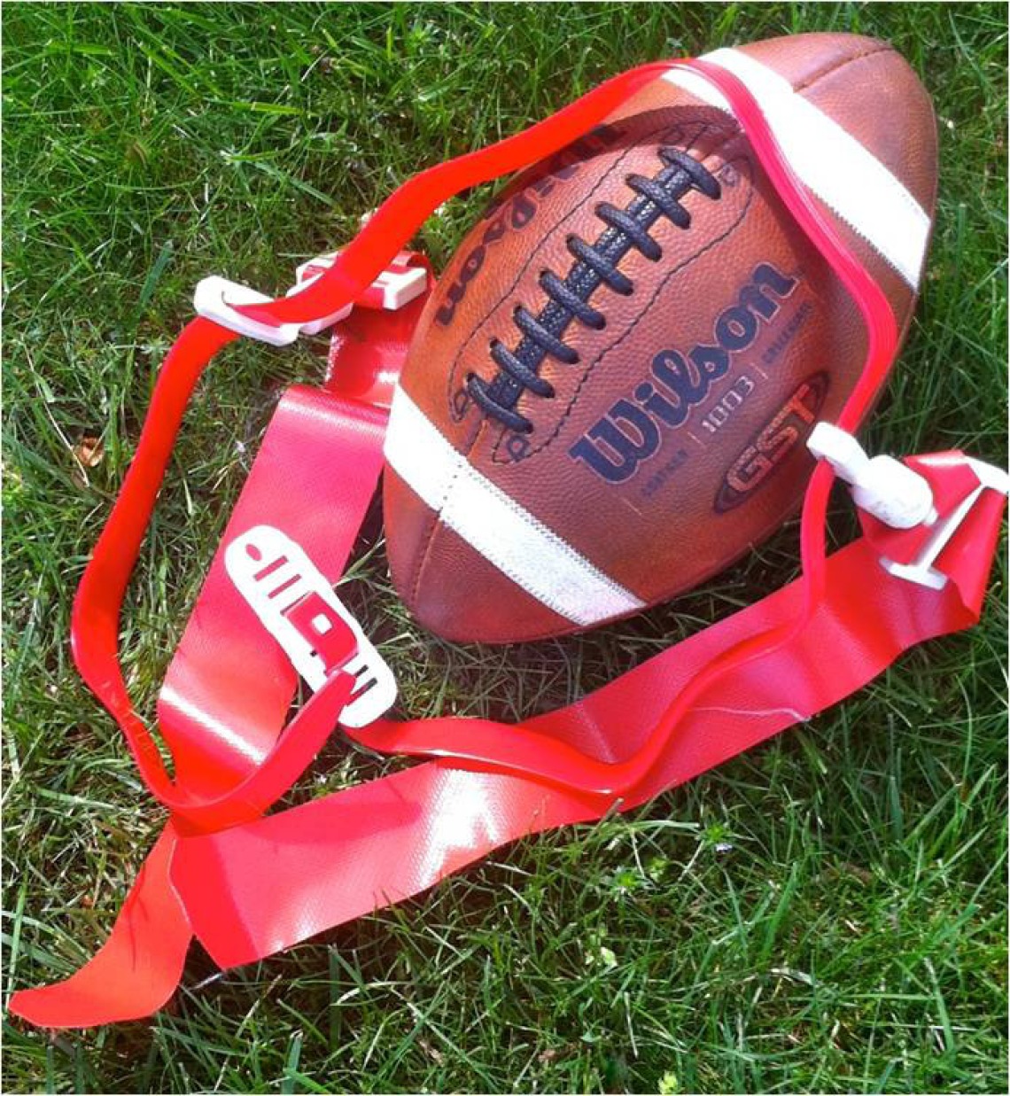 Football sitting on grass with flag football flags