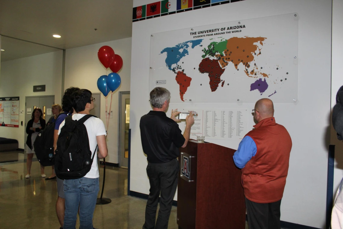 People viewing and taking pictures of "students from around the world" map at Campus Rec