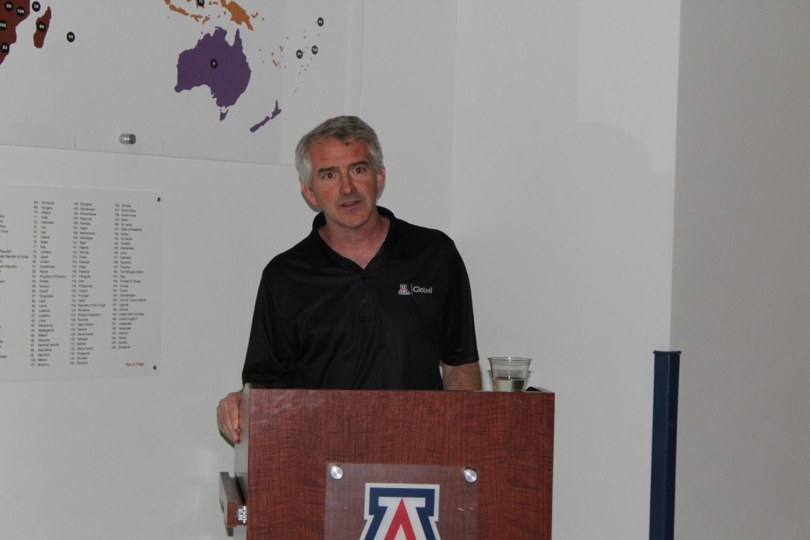 Brent White giving speech in front of "students from around the world" display