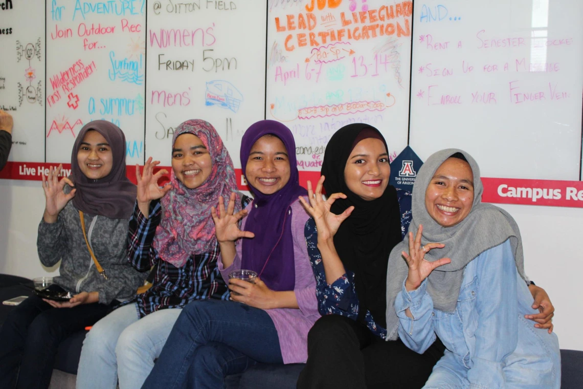 Group of students making the "c" symbol for "cats", during diversity event