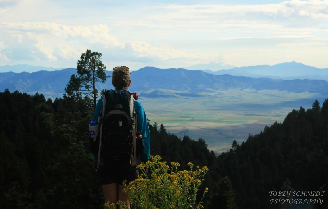 Hiker with back to camera, gazing out at mountain vista