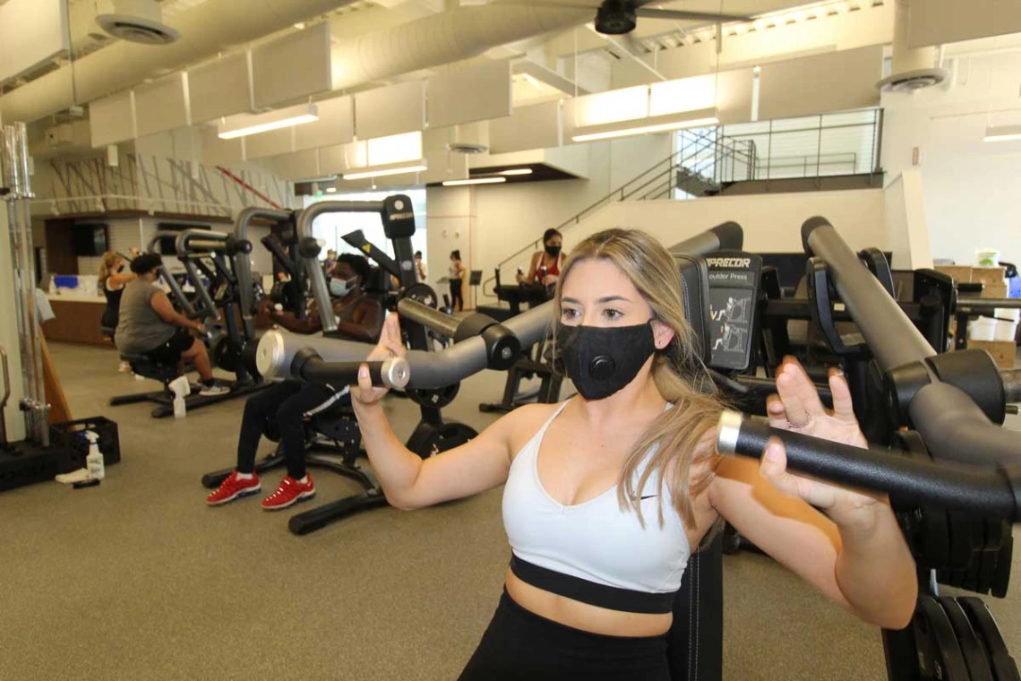 Patron wearing mask while using workout equipment alone