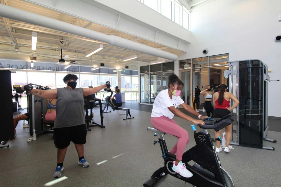 Patrons socially distance working out on machines and with free weights