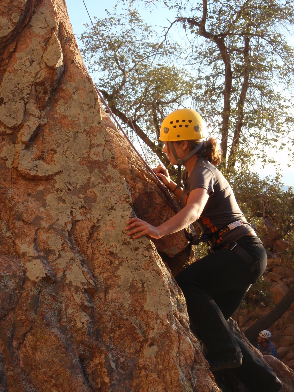 Climber beginning ascent up the side of a cliff wall