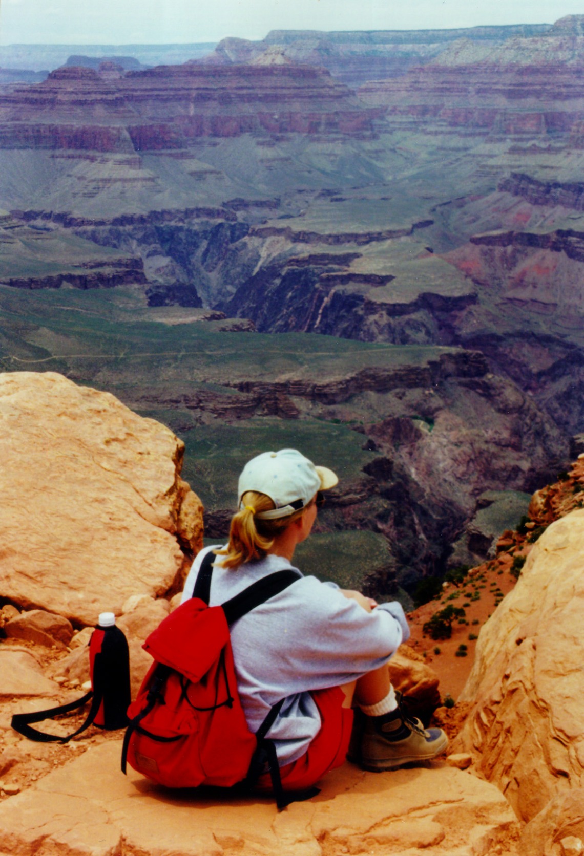 Hiker sitting on a cliff edge gazing at Grand Canyon