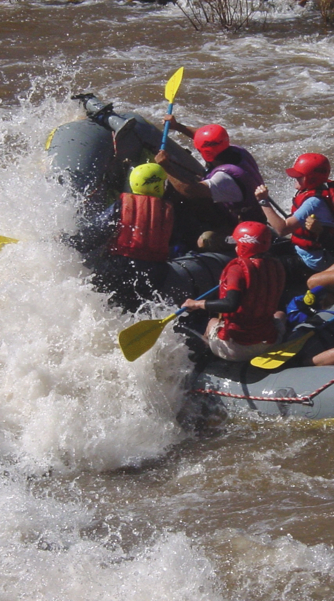 Group of white water rafters paddling into a wave