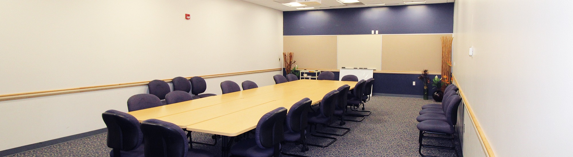 Conference table surrounded by chairs, whiteboard on the wall