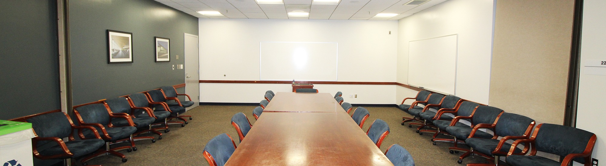 Conference room with a long table with chairs, and additional chairs against the walls