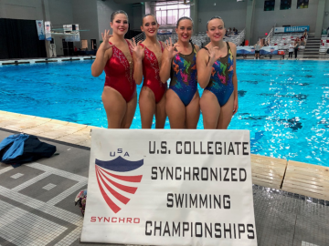 UA Synchro Swimmers standing by sign that reads: U.S. Collegiate Synchronized Swimming Championships