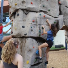 Climbers hang from bouldering wall while others watch